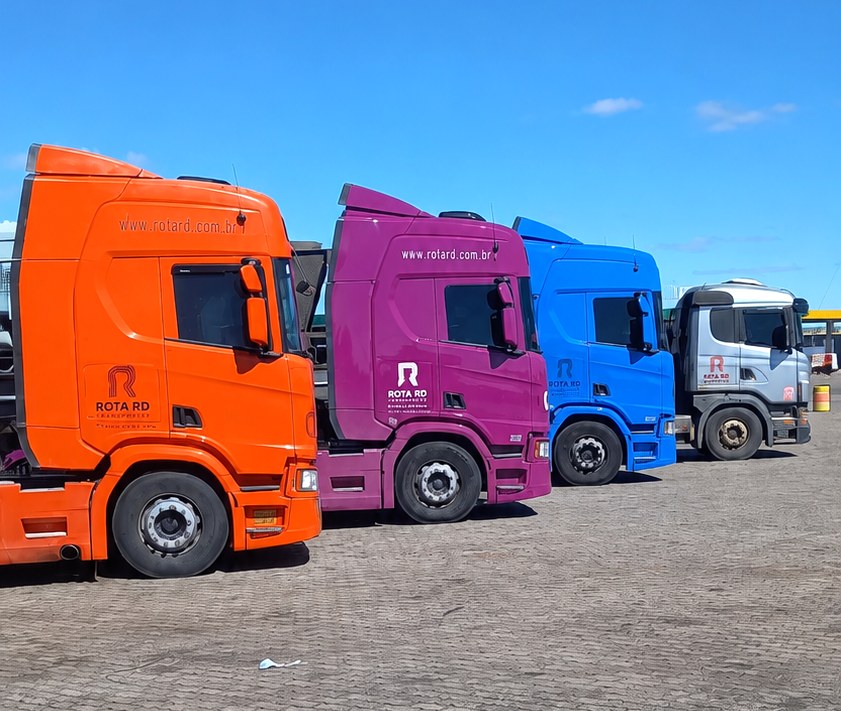 Frota Rota RD Transportes com caminhões coloridos no pátio